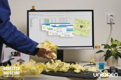 En person vid en dator täckt av gula klisterlappar med meddelandet "Jävla k*kdator" på skärmen.