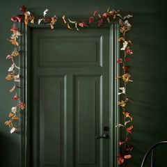 mörkgrön vägg och dörr med växtlig konstgjordgirlang som hänger runt dörrkarmarna