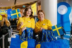 IKEA-medarbetare i gula tröjor håller svenska flaggor redo att inviga.