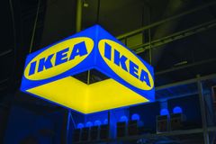 Skylt med IKEA logotypen i blått och gult hängande i ett varuhus.