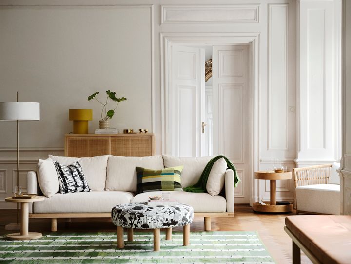 Stilfullt%20vardagsrum%20med%20ljus%20soffa%2C%20m%F6nstrad%20fotpall%2C%20gr%F6nt%20randigt%20golv%2C%20och%20moderna%20tr%E4bord.