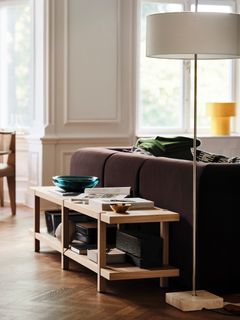 Vardagsrum med en brun soffa, ett träbord med dekorativa föremål och en golvlampa.