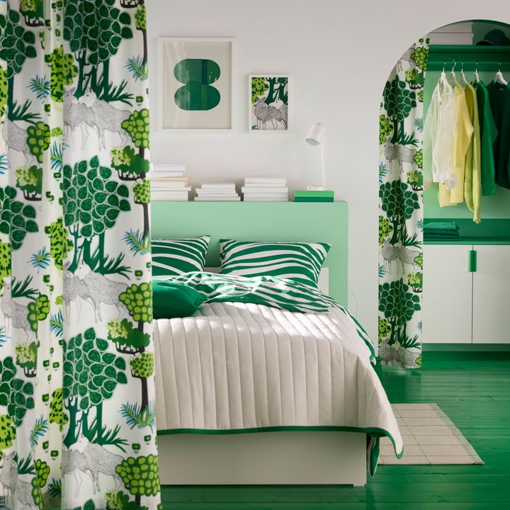 Sovrum med gröna och vita textilier, ett täcke i beige och grönt, och ett öppet klädskåp.