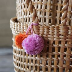 Flätad korg med två färgglada garnbollar, en lila och en orange.