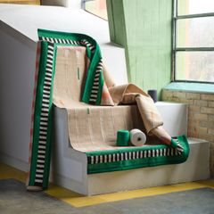 En trappa med färgglada mattor och garnrullar i grönt och beige.