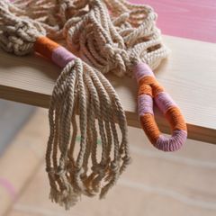 Två amplar med färgglada inslag av orange och rosa, placerade över kanten av ett ljust träbord.