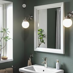 I ett badrum hänger en spegel, två lampor och en rörelsesensor på väggen.