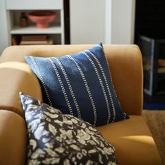 Två kuddar på en soffa, en blå med vita ränder och en med blommigt mönster.