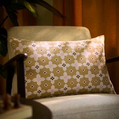En beige kudde med geometriskt mönster placerad på en beige fåtölj.