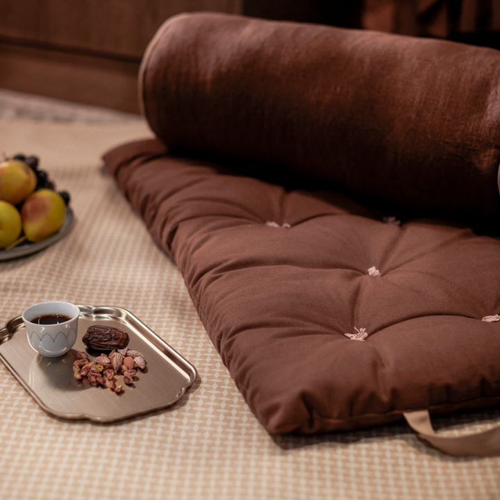 En%20brun%20go%F6vkudde%20ligger%20p%E5%20golvet%20bredvid%20en%20bricka%20med%20kaffe%20och%20snacks.