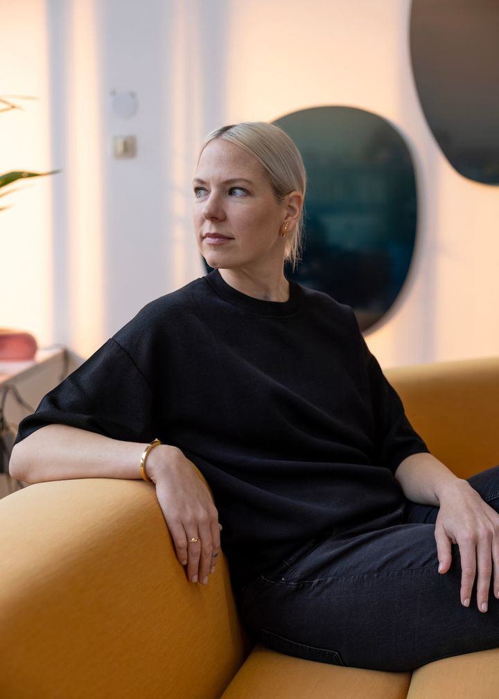 En%20person%20i%20svarta%20kl%E4der%20sitter%20i%20en%20gul%20soffa.