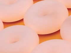 Mjuka pastellfärgade dougnuts mot en orange bakgrund.