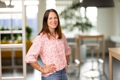 En kvinna med mörkt hår står i en kontorsmiljö.