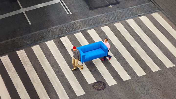 Tv%E5%20personer%20g%E5r%20p%E5%20ett%20%F6verg%E5ngsst%E4lle.%20De%20b%E4r%20p%E5%20en%20bl%E5%20soffa.