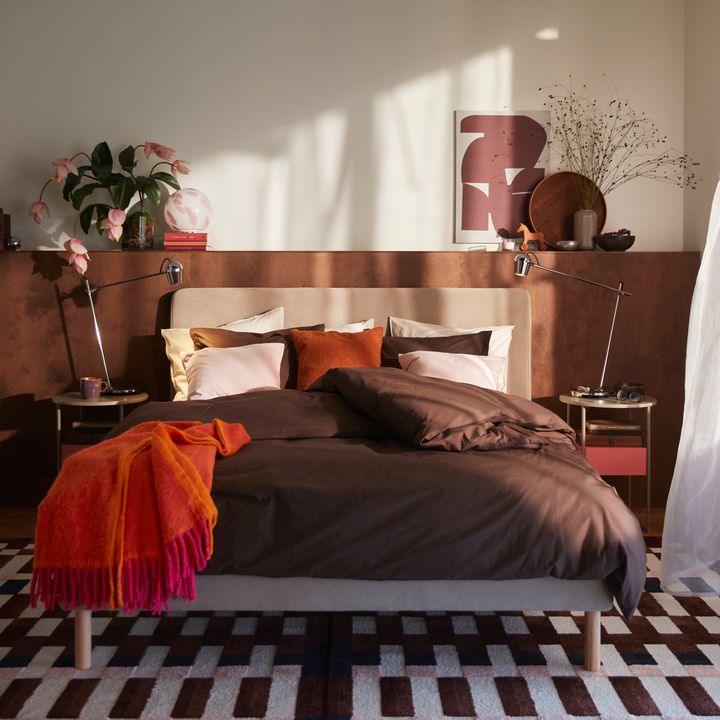 Sovrum%20med%20en%20b%E4ddad%20s%E4ng%20i%20bruna%20och%20r%F6da%20toner%2C%20omgiven%20av%20lampor%20och%20dekorationer.