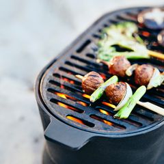 Grill med grönsaks- och köttspett över glödande kol.