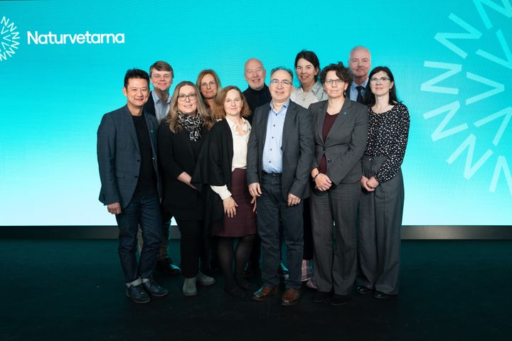 En grupp människor står framför en blå bakgrund med texten "Naturvetarna".