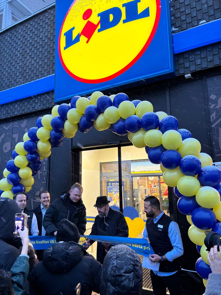 Premiär för Lidl i Hallonbergen. När klockan slog 08:00 klippte Sundbybergs kommunstyrelseordförande Peter Shilling, tillsammans med Thomas Andersson, regionsdirektör för Lidl Sverige, bandet och förklarade butiken öppnad inför en skara köpsugna konsumenter i snörusket.