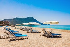 Solstolar och parasoller på en sandstrand med berg i bakgrunden, Alanya, Turkiet.