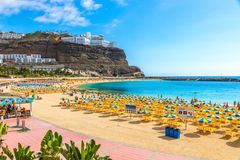 En strand på Gran Canaria med gula och blå parasoller.