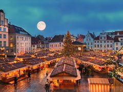 Julmarknad på ett torg med upplysta stånd och en stor julgran i Tallinn centrum.