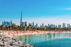 Strand i Dubai med stadssilhuett och klarblå himmel.