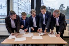 En grupp män vid ett bord som granskar dokument tillsammans.