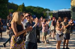 Grupp människor som applåderar på utomhusfestivalen Way Out West i Slottsskogen en solig dag.