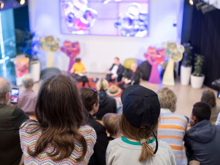 Grupp av människor sitter och lyssnar på ett panelsamtal i en sal med färgglada dekorationer på Vetenskapsfestivalen.