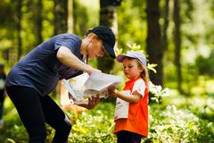 En vuxen och ett barn tittar tillsammans på en orienteringskarta i skogen.