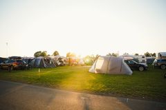 Tält, husvagnar och bilar på en campingplats i kvällssol under O-Ringen.