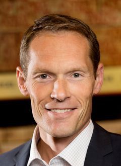 Man i kostym ler mot kameran.