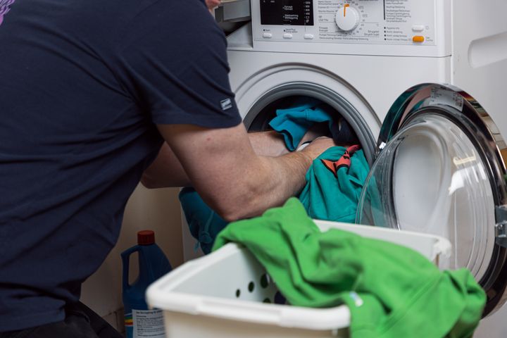 Närbild på tvätt som läggs in i en tvättmaskin