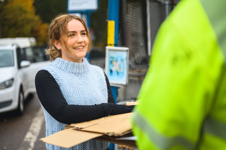 En ung kvinna lämnar in kartongbitar till återvinning