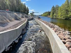 Fiskvägen som löper parallellt med förbindelsen mellan Sommen och Svartån. fiskvägen avgränsas med betongfundament. Vattnet i fiskvägen strömmar och glittrar i solen.