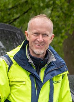 Leende medelålders man i gul och grå varseljacka med Tekniska verkens logga