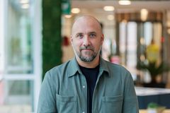 Porträttbild i liggande format, halvfigur, Johan Borg med skägg, rakat huvud och grön skjorta