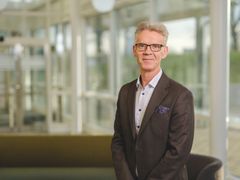 Man med glasögon och grått hår mörkgrå kavaj, halvfigur