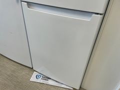 Ett vitt kylskåp i ett kök med en droppmatta som sticker ut undertill, märkt med logotypen “Tekniska Verken”.