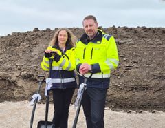 En man och kvinna i gula varseljackor står bredvid varandra och håller i varsin spade