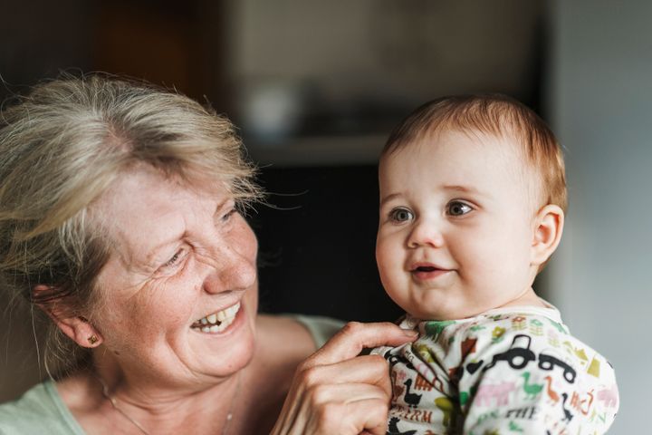 Äldre kvinna håller ett leende barn i famnen.