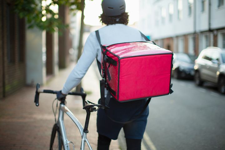 Ett cykelbud promenerar med sin cykel.