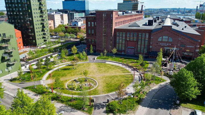 Grönskande park som kan omhänderta skyfall, omgiven av äldre och moderna byggnader i Lindholmen Innovation District.