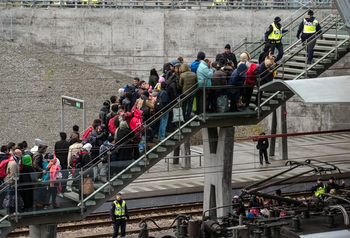 Folk köar på en trappa vid en tågstation, medan poliser övervakar.