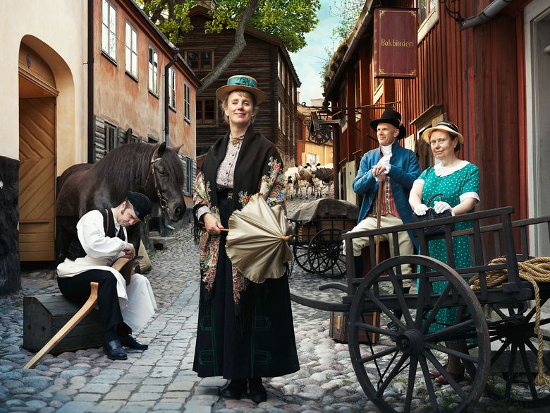 Historiskt klädda personer tillsammans med häster och kor i Skansens Stadskvarter.