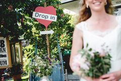 Drop in-bröllop skylt med en vitklädd brud i förgrunden.
