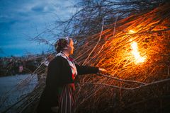 En folkdräktsklädd kvinna tänder majbrasan på Skansen.