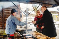 Ett par köper kolbullar som en kvinna tillverkar över  öppen eld på Skansens julmarknad.