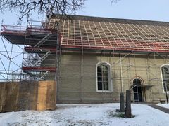 Grå stenkyrka med byggnadsställningar för takrenovering