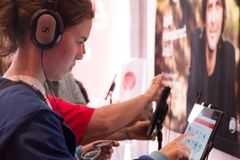 Ung kvinna med hörlurar kollar hörseln med Hörseltestaren.